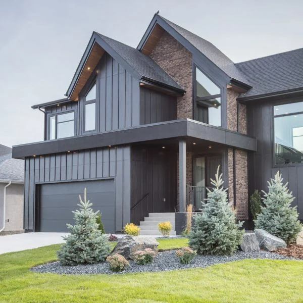 Modern dark-sided home with steep gables, brick accents, and evergreen landscaping