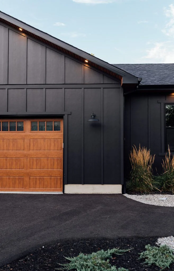 Dark vertical siding alongside a warm wood garage door